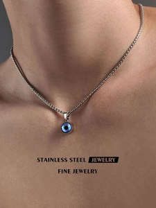 Detail of blue Evil Eye pendant on wheat chain necklace worn by a male model