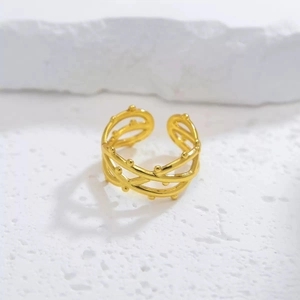 Detail of a golden multi-layer braided ring with delicate bead texture on stone surface