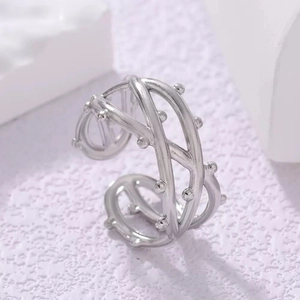 Macro shot of silver titanium steel X-shaped ring with textured beads and open design