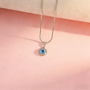Detailed close-up of a silver snake chain necklace with a blue evil eye pendant charm