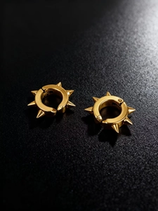 Vue macro de boucles d'oreilles punk dorées avec rivets sur fond noir texturé