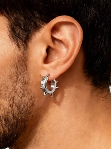 Gros plan macro d'une boucle d'oreille punk à pointe argentée sur l'oreille d'un homme