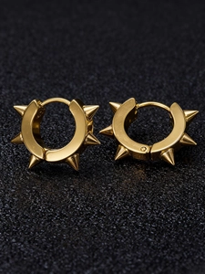 Vue macro de boucles d'oreilles punk dorées en acier inoxydable avec des clous