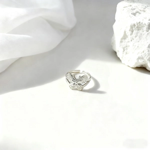 Anillo geométrico plateado de mariposa con detalles en relieve y diseño abierto