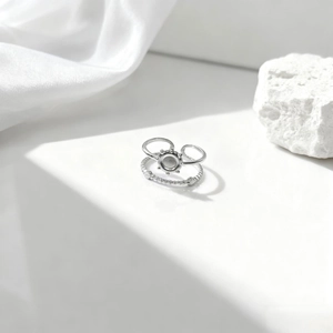 Detalle del conjunto de anillos plateados con diseño de sol sobre seda blanca