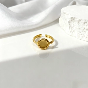 Primer plano de anillo ovalado dorado hueco con textura trenzada en seda blanca