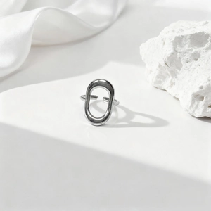 Anillo minimalista plateado ovalado hueco con banda ajustable sobre seda blanca