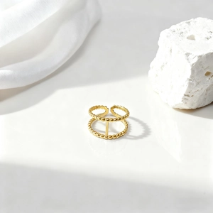 Detalle de anillo dorado de doble capa con cuentas sobre seda blanca y piedra mineral