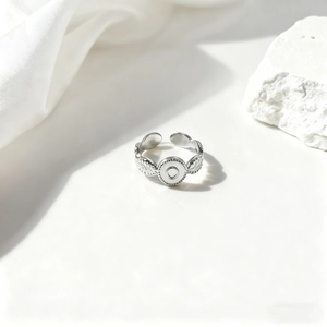 Detalle de anillo de plata con hoja de laurel, disco central y texturas de calado precisas