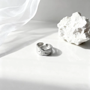 Vista macro detallada de un anillo de hoja plateado con diseño de ojo en piedra blanca