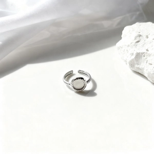 Detalle de anillo ajustable de acero plateado con textura de microperlas sobre piedra