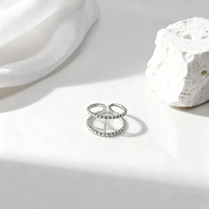 Detalle del anillo de plata de doble capa con cuentas sobre piedra blanca y seda