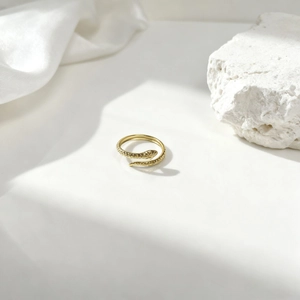 Detalle de anillo de serpiente dorado con textura de escamas sobre seda y piedra
