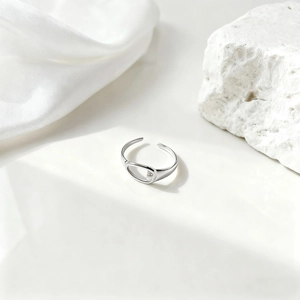 Detalle de anillo de laurel plateado sobre seda, diseño ovalado hueco y fino