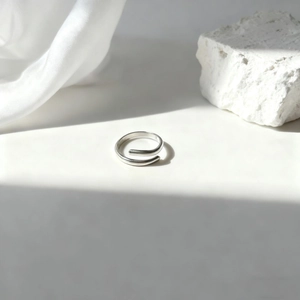 Vista macro detallada de un anillo espiral plateado sobre seda blanca y piedra