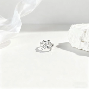 Detalle del juego de anillos de plata orgánica sobre seda blanca y textura de piedra