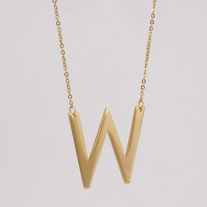 Detalle de un collar minimalista dorado con un colgante en forma de letra W mate