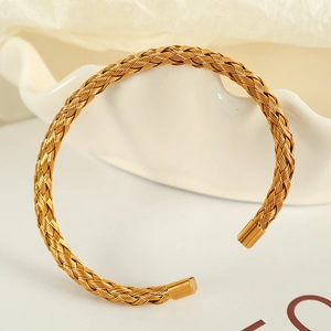 Dettaglio della trama a maglia intrecciata dorata su un bracciale aperto in acciaio inox