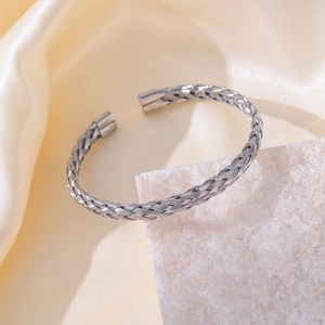 Dettaglio di un bracciale a fascia aperta in acciaio inossidabile intrecciato su seta e pietra