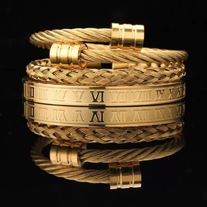 Detail view of gold stainless steel stackable bracelets with Roman numerals and woven texture