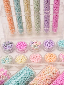 Macro shot of 2-6mm colorful macaron glass pebbles in jars for DIY jewelry making