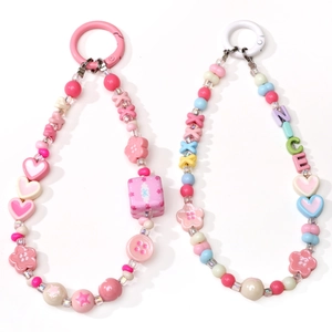 Close-up of handmade acrylic XOXO and heart bead phone charms with colorful floral elements