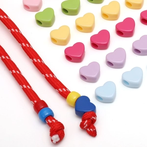 Dettaglio macro di perline acriliche colorate a forma di cuore infilate su una corda intrecciata