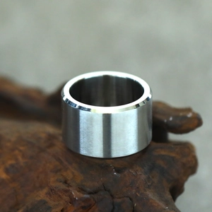Macro shot of brushed stainless steel ring with polished edges on wood texture