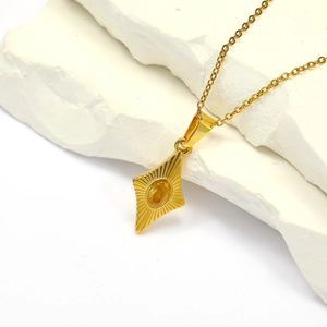 Detail of gold necklace featuring diamond-encrusted geometric pendant with yellow stone