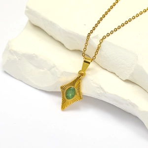 Detail of vintage gold necklace with green oval stone and sunburst texture pendant