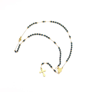 Détail du collier chapelet avec perles bleues facettées et pendentif croix dorée