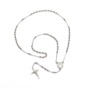 Détail du collier à perles argentées avec une médaille de la Vierge et pendentif croix