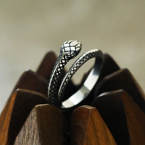 Macro shot of titanium steel snake ring with detailed scales on a dark wooden base