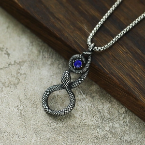 Détail du pendentif serpent vintage avec écailles texturées et pierre bleue sur chaîne