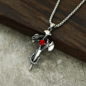 Collier pendentif serpent gothique avec croix et pierre rouge sur fond en bois