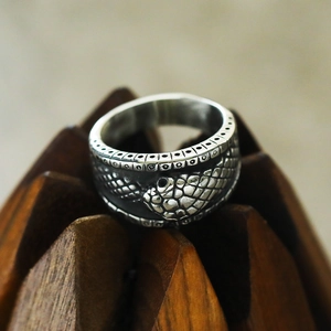Macro detail of retro snake ring with intricate scales on textured wooden stand