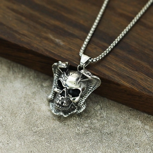 Détail macro du pendentif crâne gothique et double cobra en acier avec finition argent vieilli