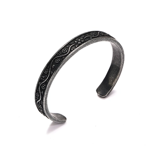 Detailed relief of vintage floral vine patterns on a retro steel cuff bracelet