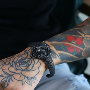 Close-up of vintage lion head viking bracelet on man's tattooed wrist with oxidized finish