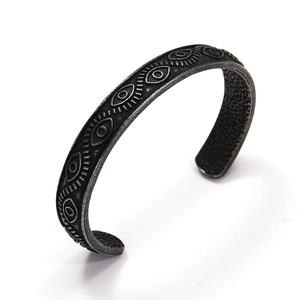 Macro view of vintage Viking cuff bracelet with etched eye patterns and matte finish