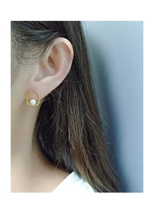 Detail eines eleganten goldenen Ohrrings mit weißer Perle am Ohr eines Models