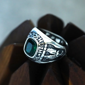 Close-up of vintage steel class ring featuring green gemstone and eagle relief carvings