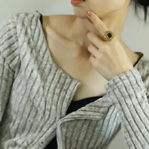 Detail shot of vintage gold ring with square emerald green stone on a model's hand