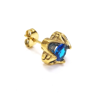 Detail van vintage gouden oorknopje met blauwe edelsteen en getextureerde golvende vorm