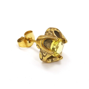 Detail van vintage gouden oorknopje met gele edelsteen en reliëfpatroon op metaal
