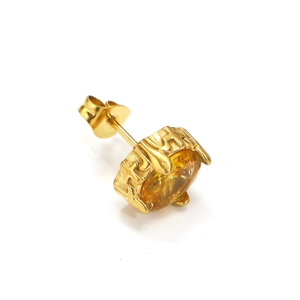 Makroaufnahme von goldenem Kreuz-Ohrstecker mit bernsteingelbem Zirkon und Textur