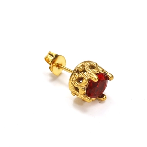 Détail macro d'une boucle d'oreille vintage dorée avec une grande gemme rouge