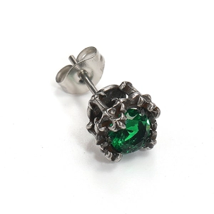 Macro shot of a dark green zircon stud earring with vintage textured metal claw