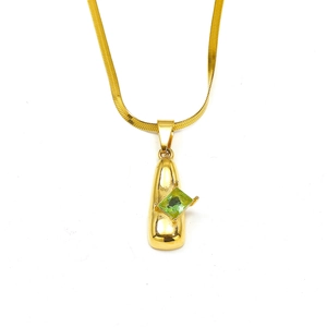 Detalle del collar de cadena de serpiente dorada con colgante de gema verde