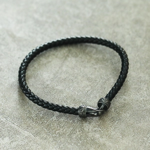Détail du bracelet en cuir tressé noir avec fermoir crochet argenté vintage gravé